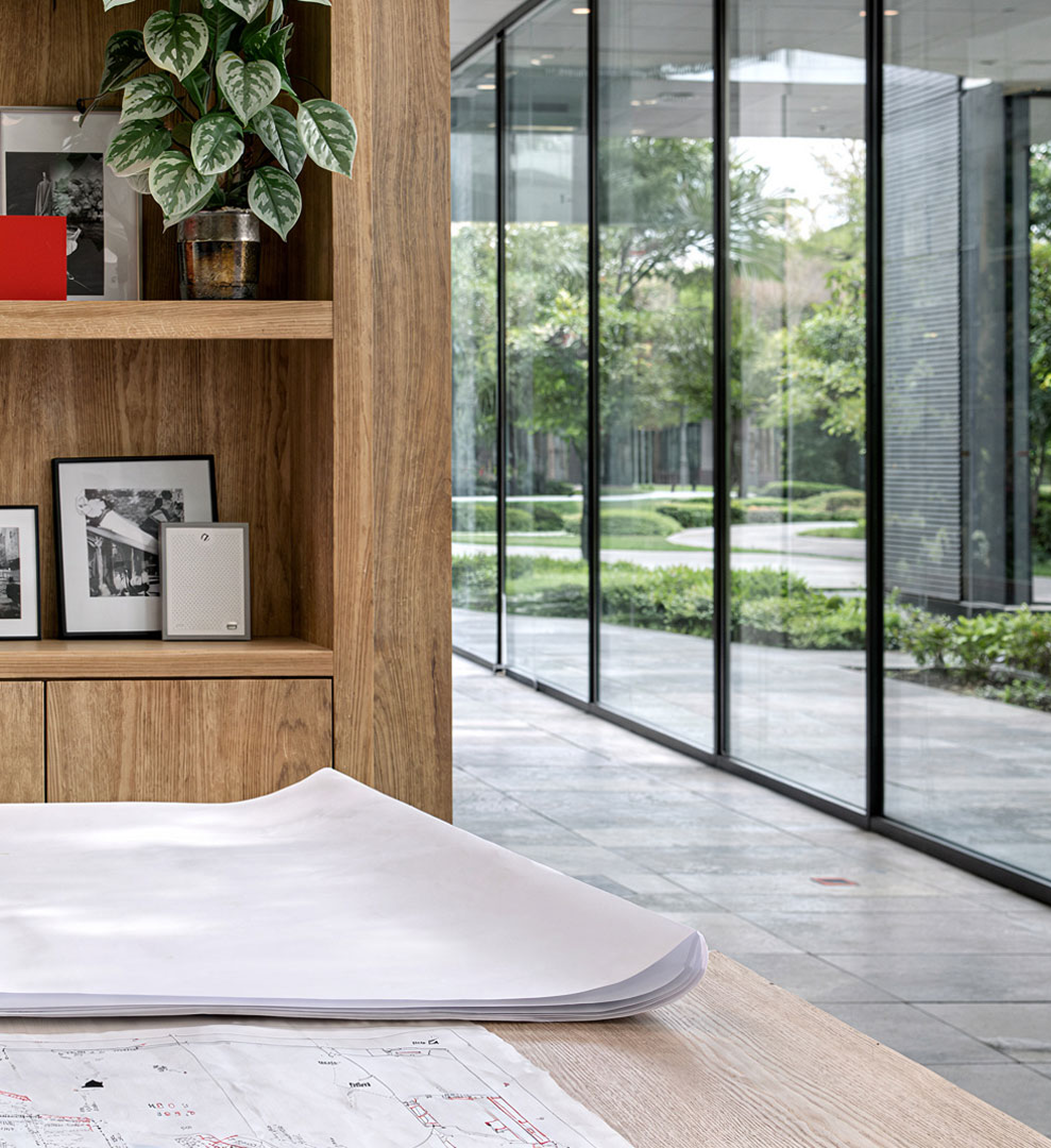 Architectural workspace with shelving, plans, and glazed garden view